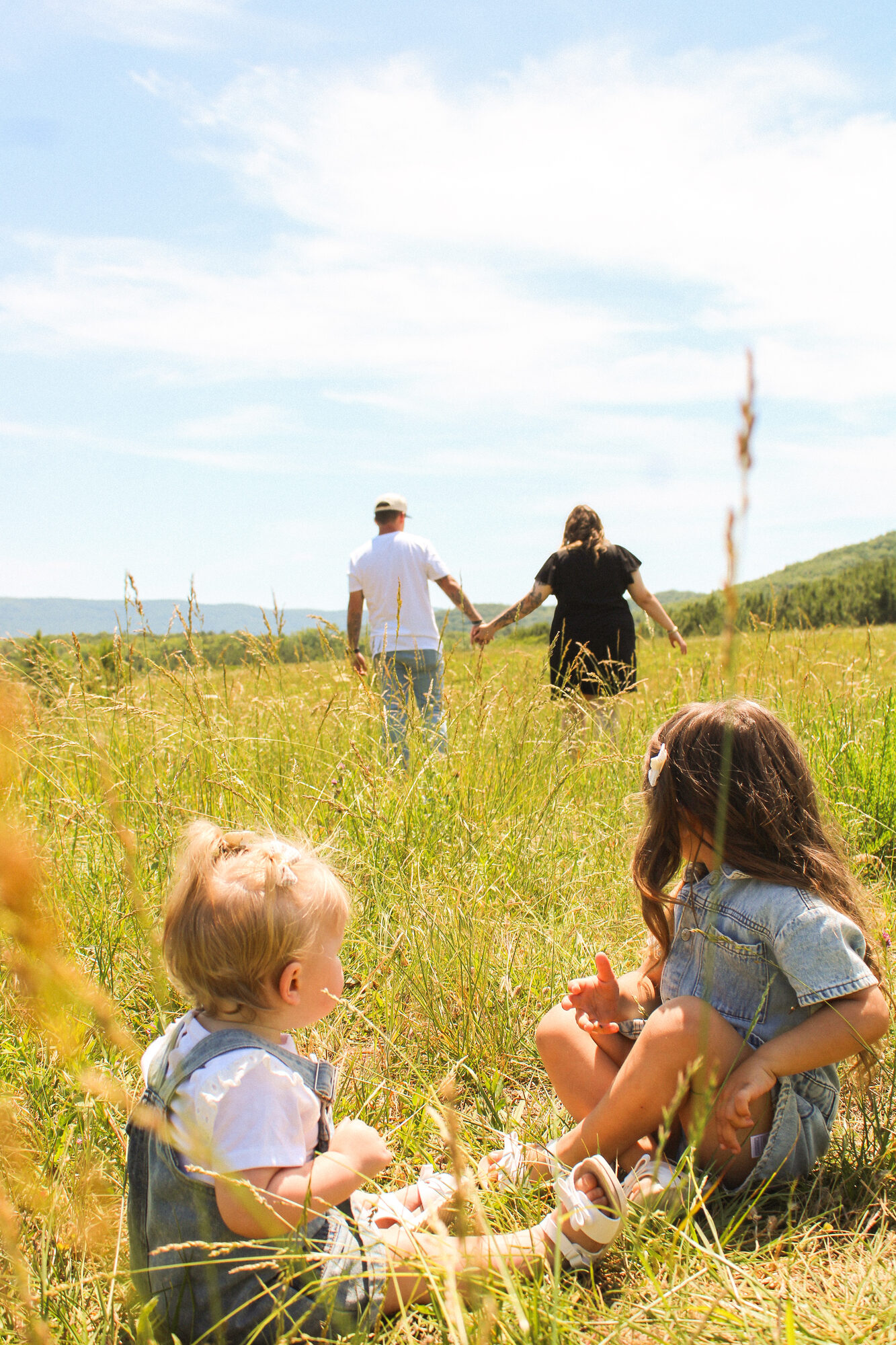 Family walking through a sunlit meadow, photographed by Pics by Madi